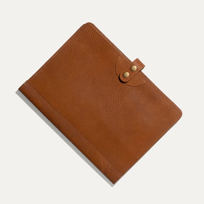 Tan full-grain leather journal cover with brass snap closure on light background