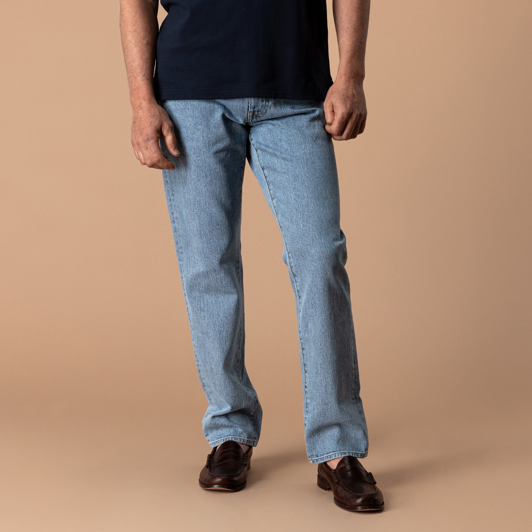 Men's light wash straight fit denim jeans worn with dark brown penny loafers