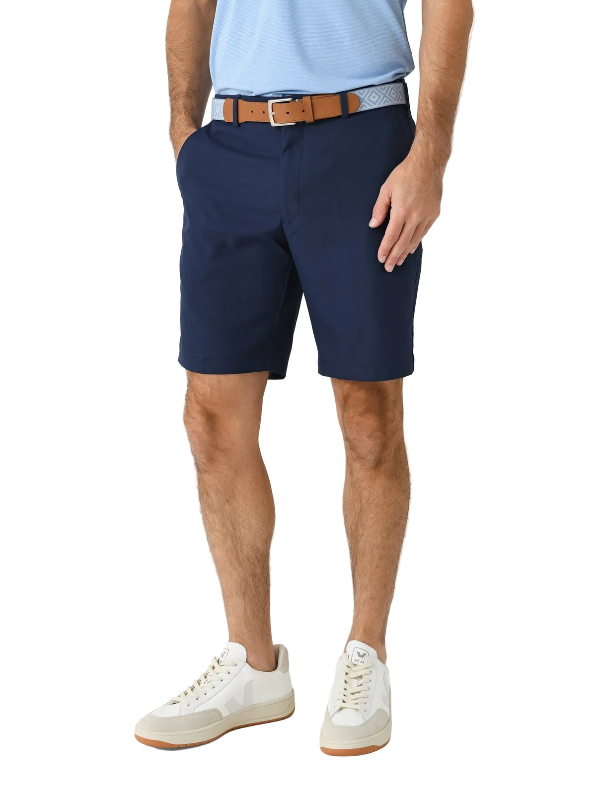 Men's navy blue performance chino shorts with brown belt and white sneakers