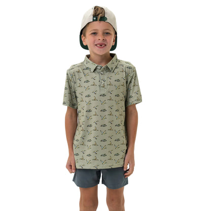 Boy wearing sage green polo shirt with allover flying ducks print and grey shorts