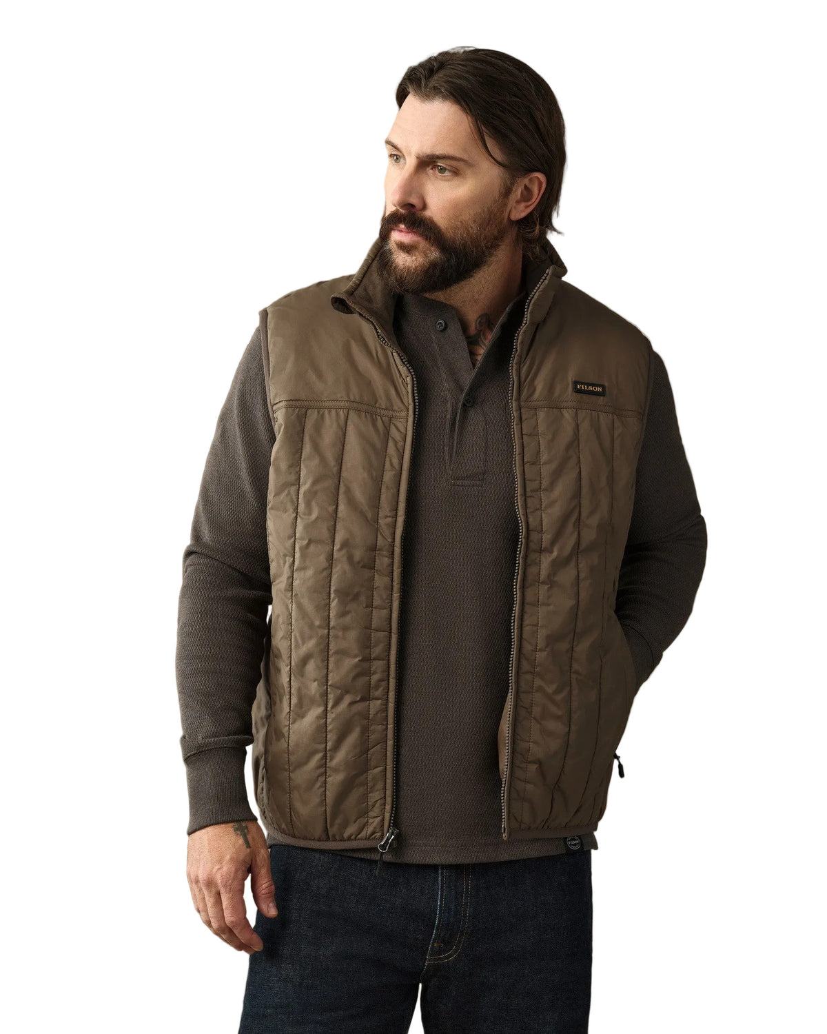 Man wearing olive quilted Filson Ultralight Vest over dark gray quarter-zip pullover
