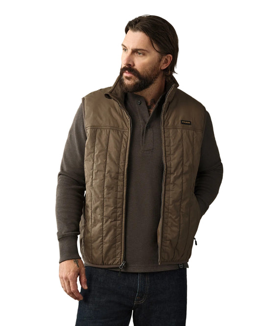 Man wearing olive quilted Filson Ultralight Vest over dark gray quarter-zip pullover